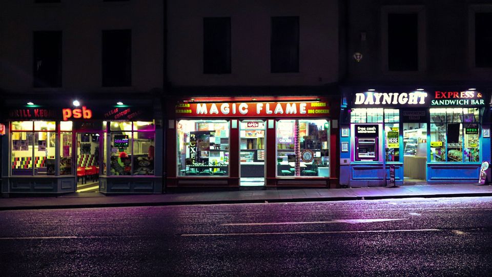 Three fast food outlets illuminated by lights.