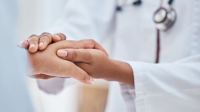 A close up of a doctor holding a patient's hand.
