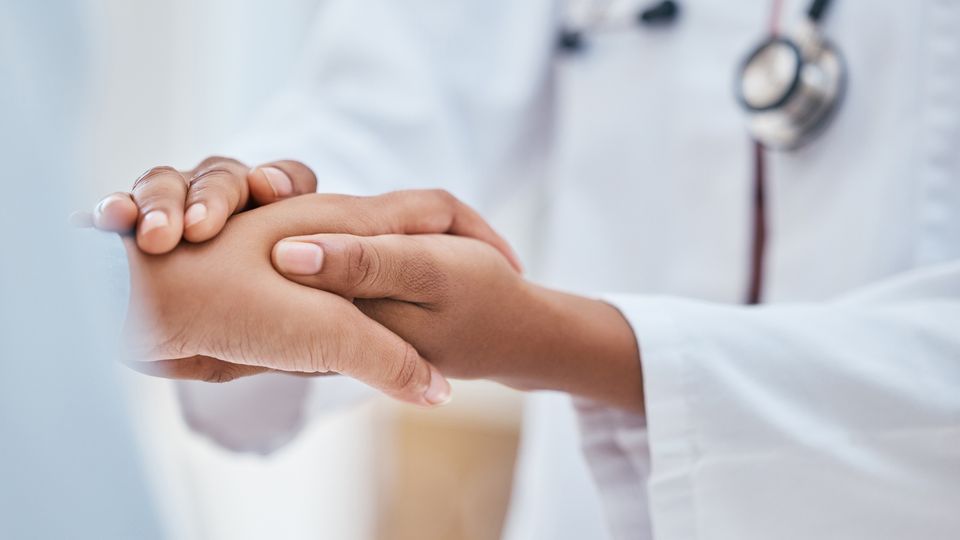 A close up of a doctor holding a patient's hand.