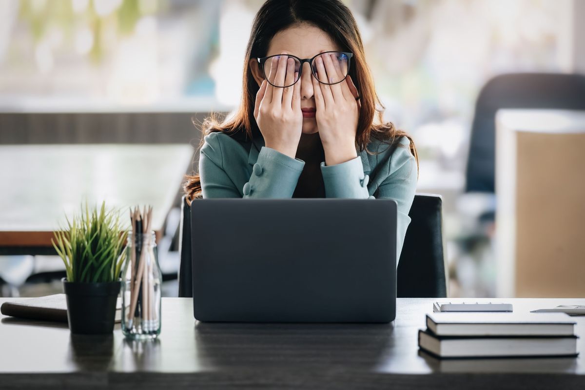 Burnout is incredibly prevalent in STEM. A person holding their head in their hands, looking tired.