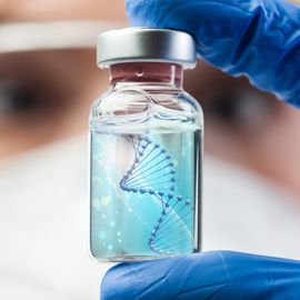 A lab scientist holding a glass vial containing a liquid with a DNA strand 