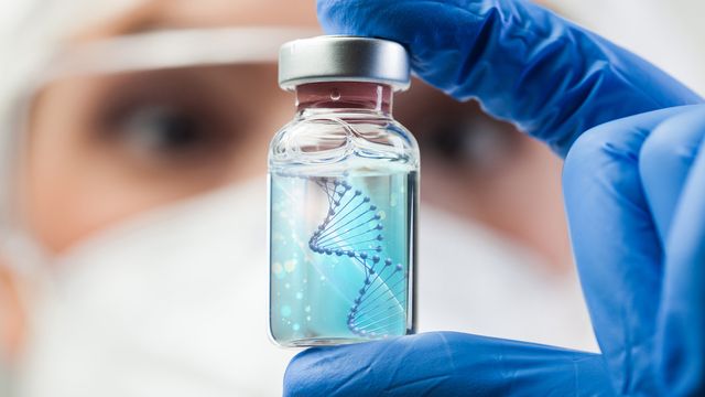 A lab scientist holding a glass vial containing a liquid with a DNA strand 