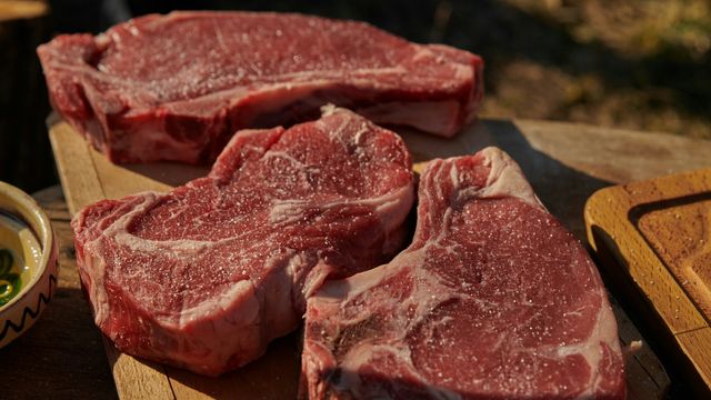 Three steaks on a wooden board.