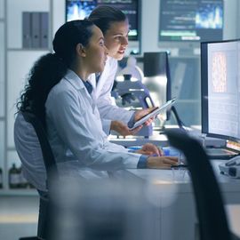 Two scientists work on a computer in a lab. 