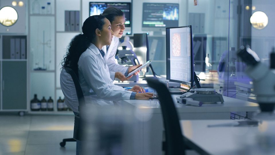 Two scientists work on a computer in a lab.